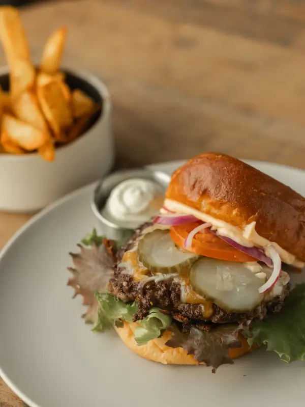 Burger på tallerken med en skål med pomfritter